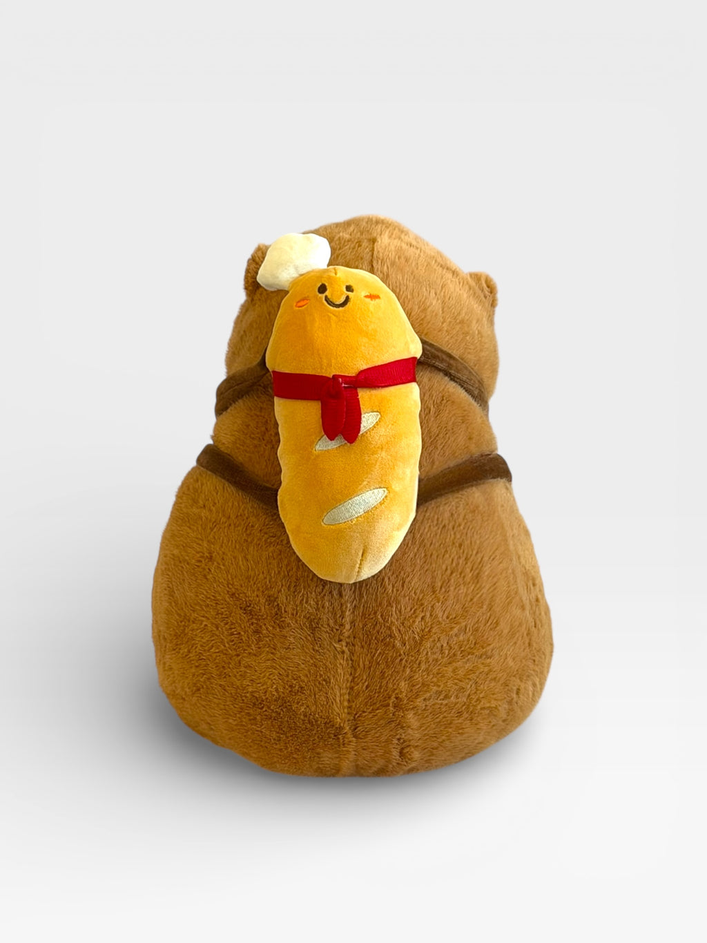 Plush toy resembling a Capybara with a bread slice on its back against a white background