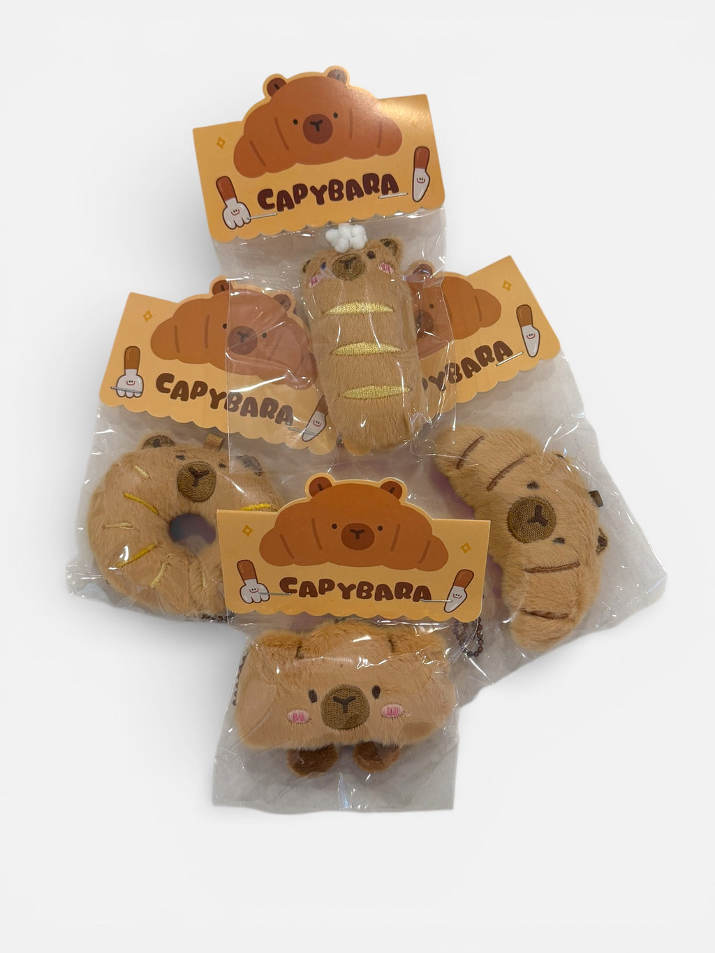 Capybara-themed plush toys in packaging on a white background