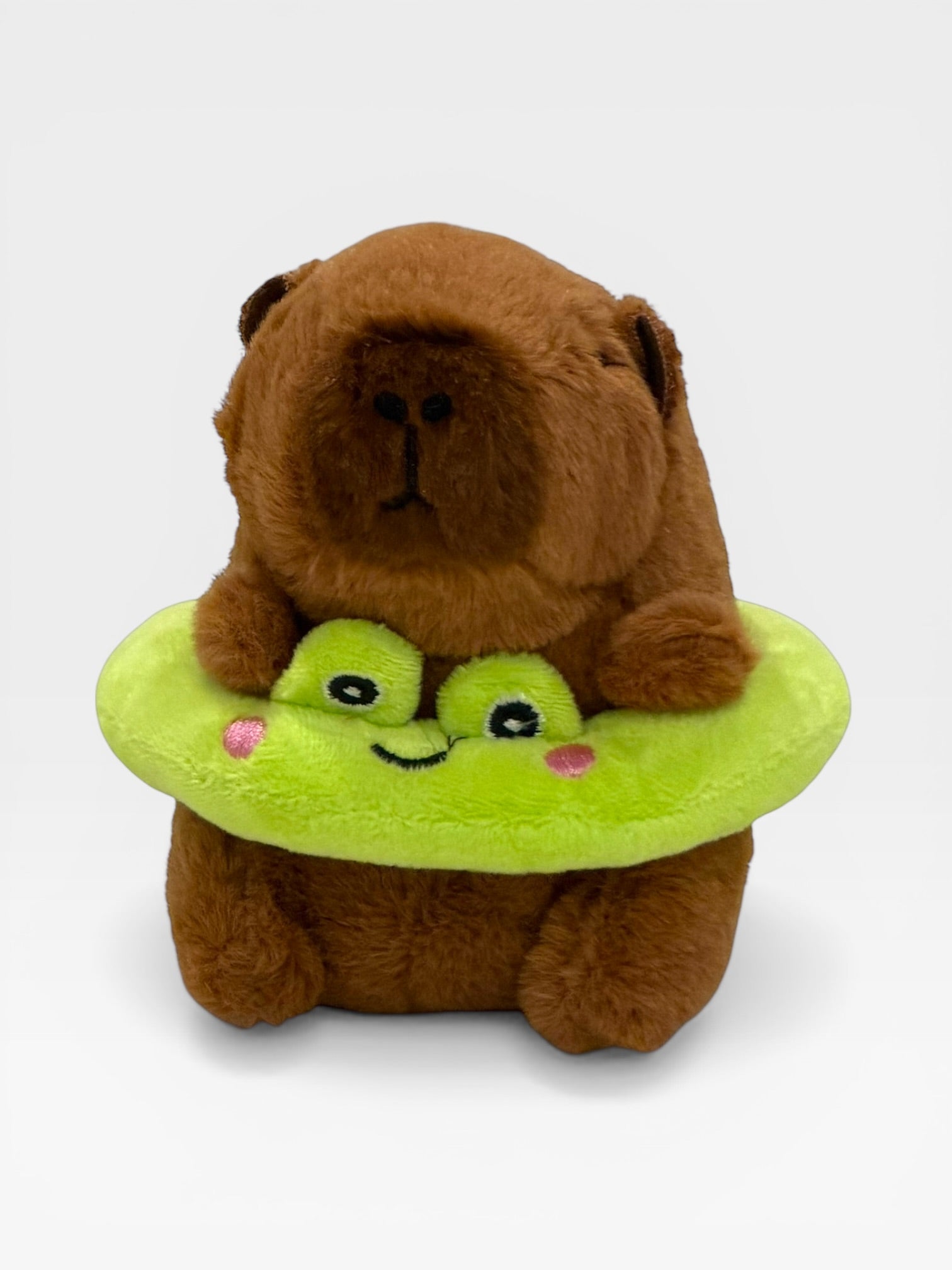 Plush toy Capybara sitting on a green frog with a white background
