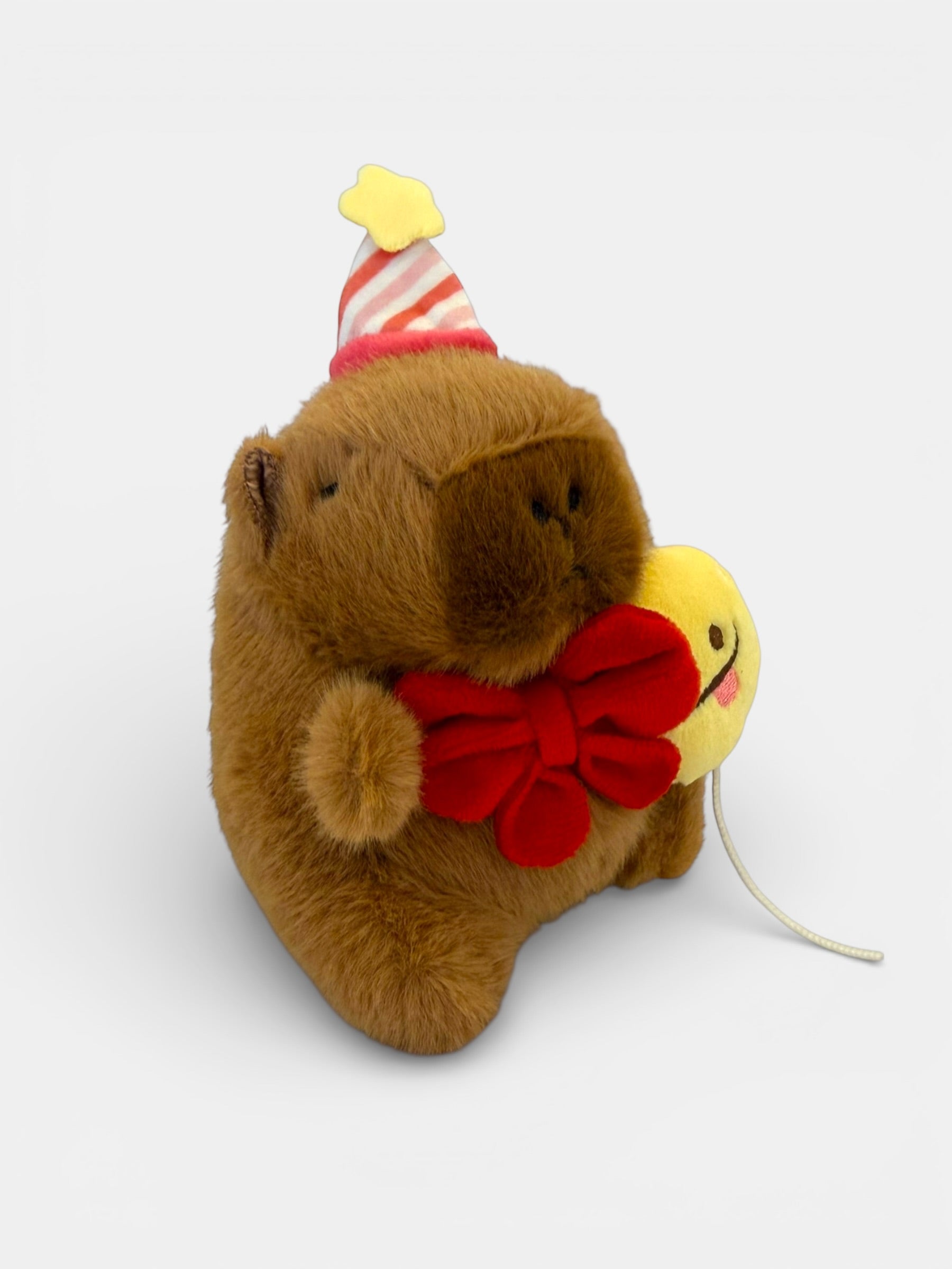 Plush toy Capybara with a party hat and yellow duck on a white background