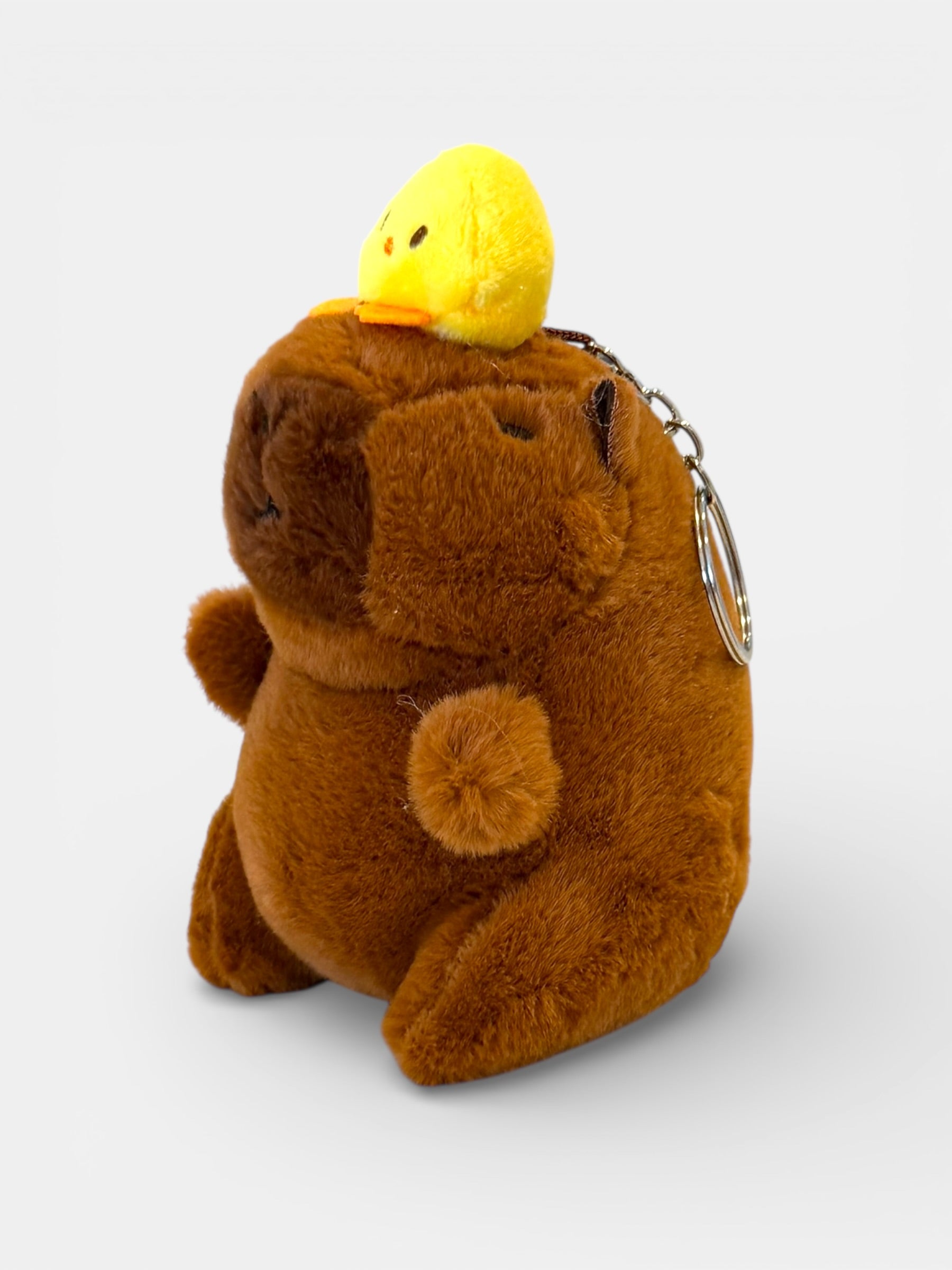 Plush bear keychain with a yellow duck on its head against a white background