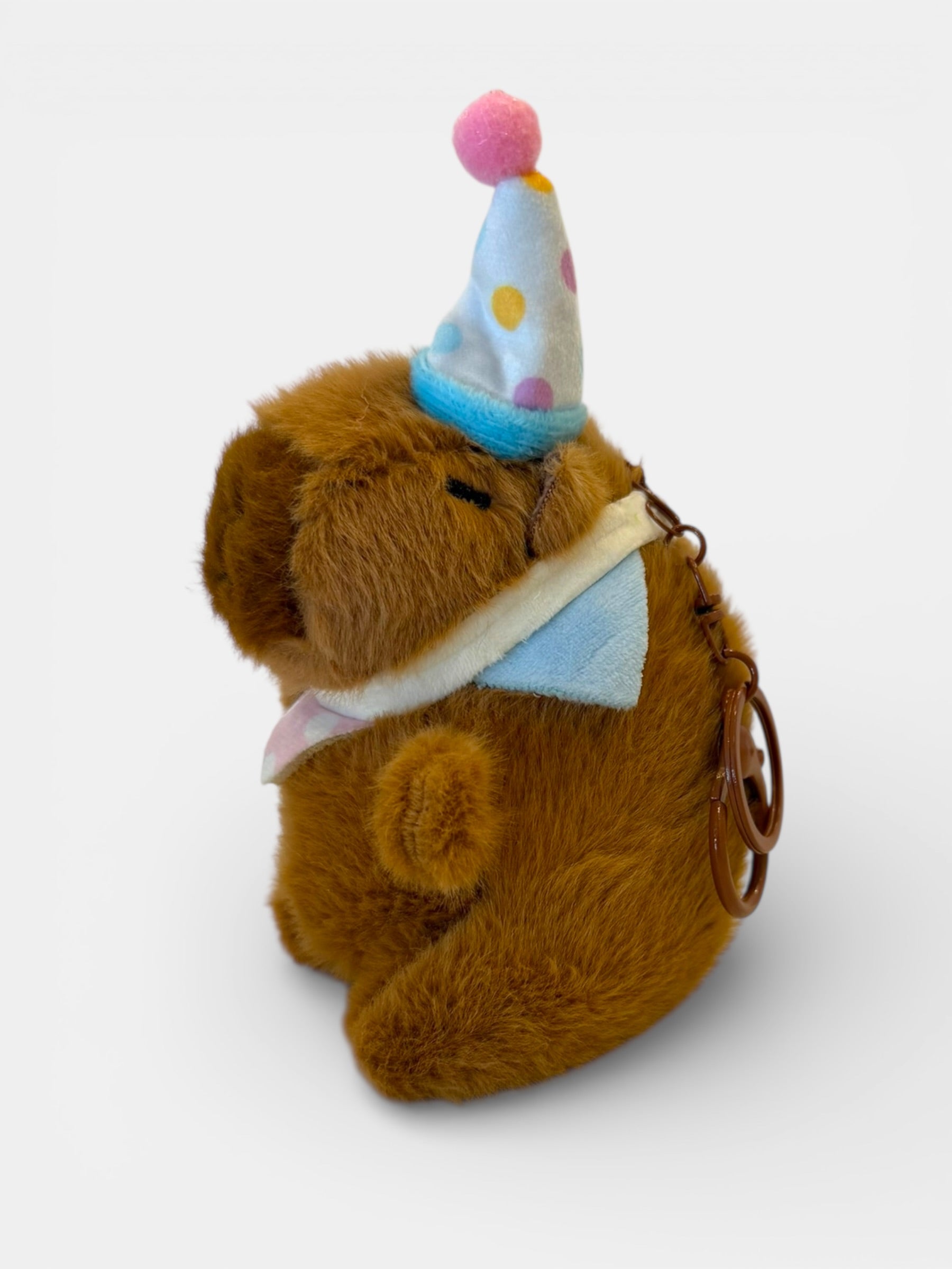 Brown teddy bear keychain wearing a party hat on a white background