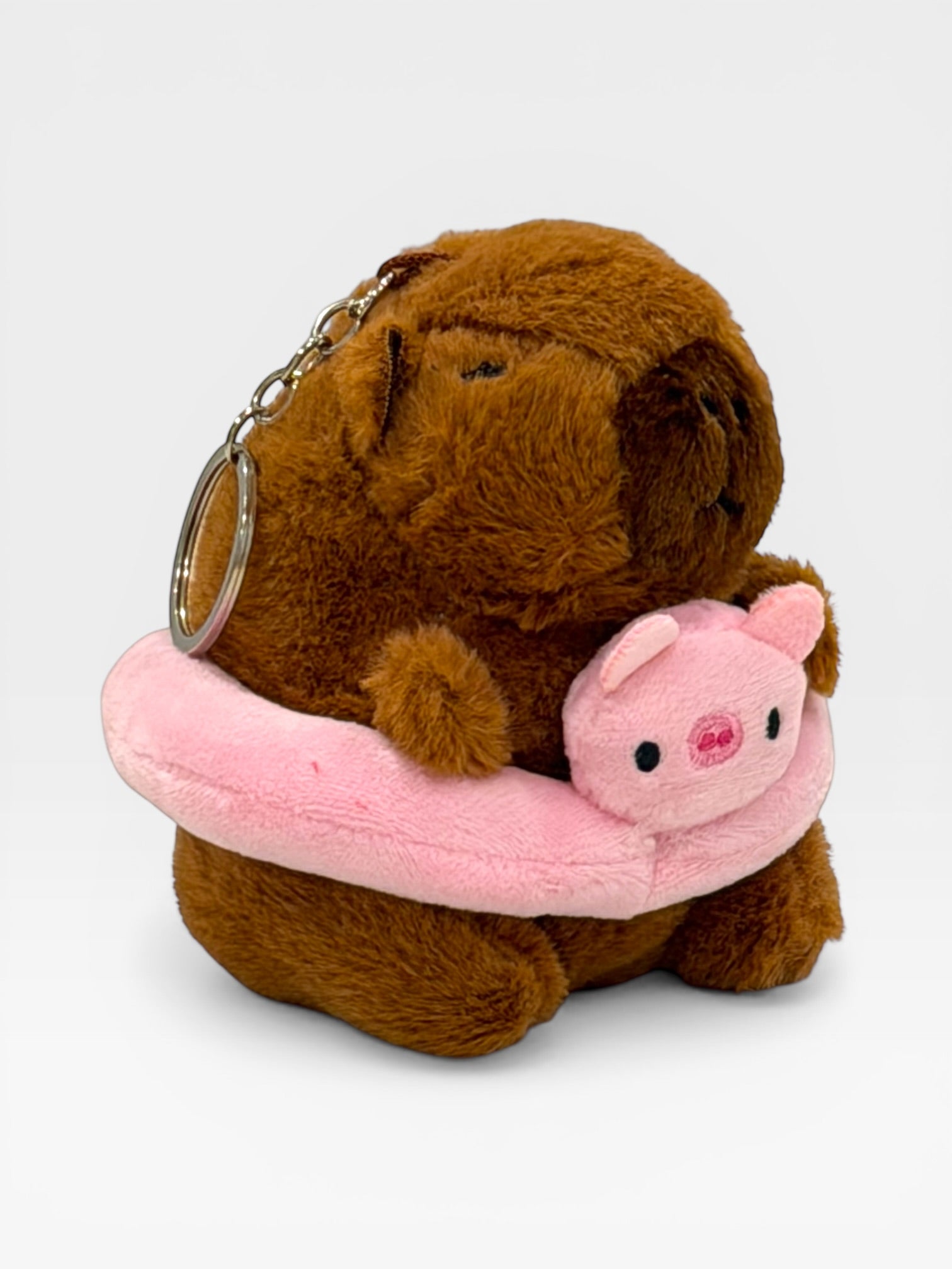 Plush keychain with a brown bear holding a pink piglet on a white background