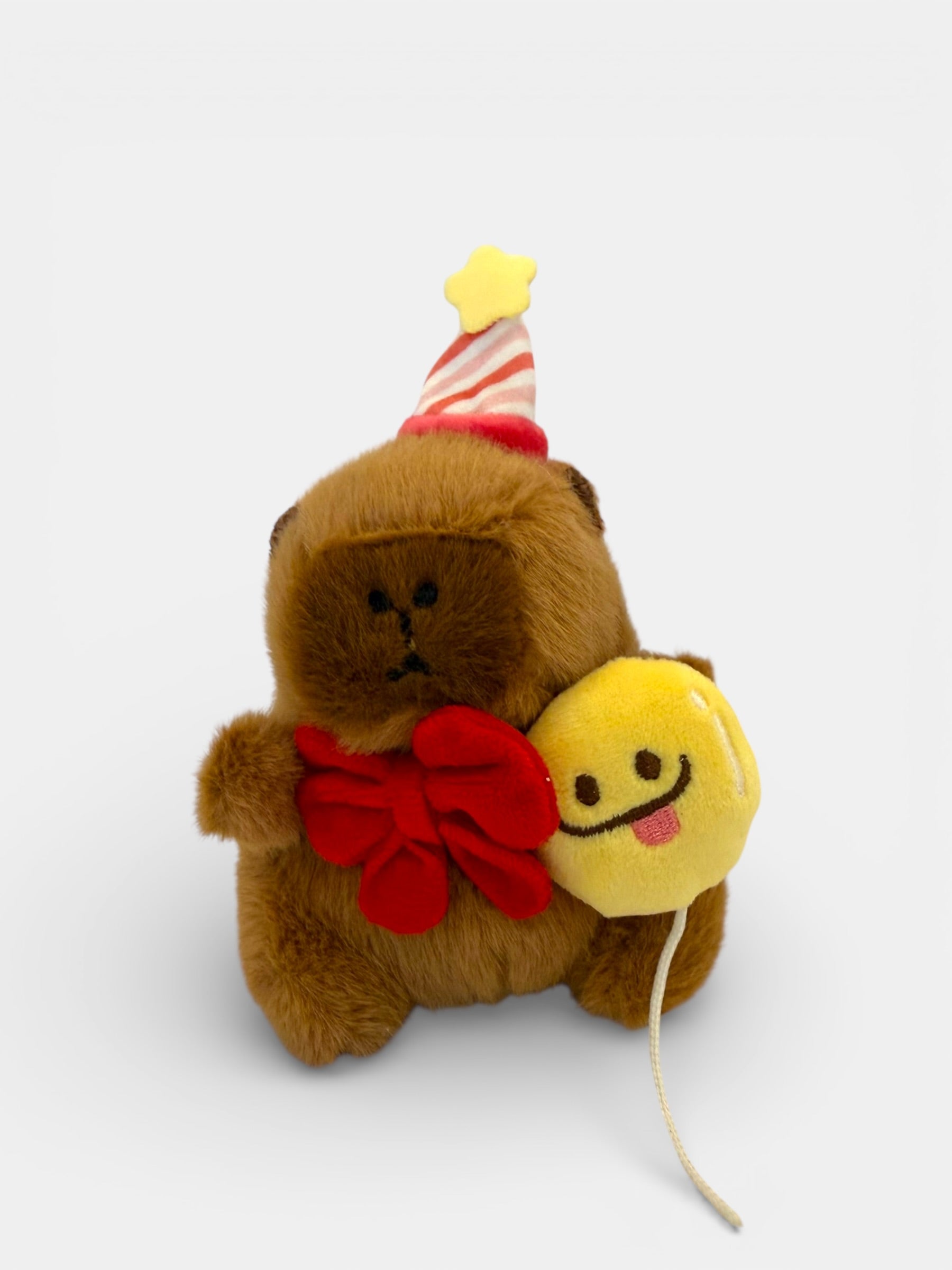 Capy Plush Keychain toy with a party hat, red bow, and balloon on a white background