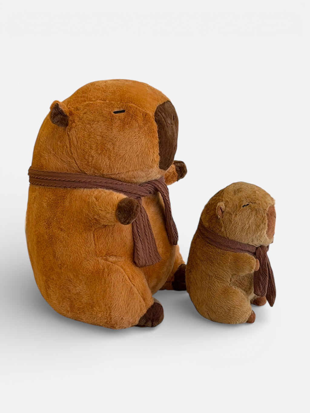 Two brown plush Capybaras with scarves 